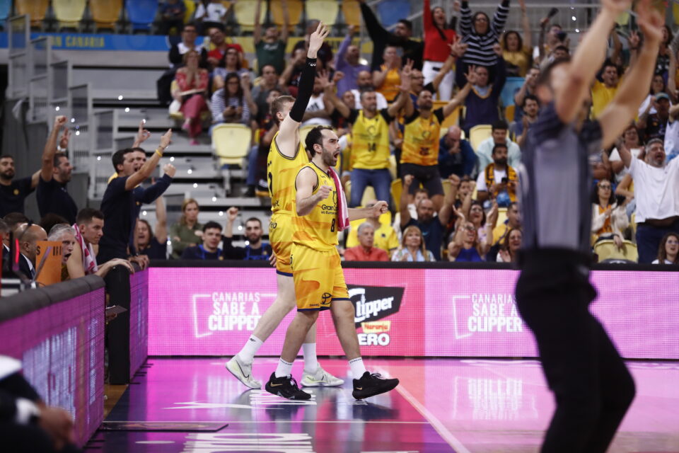 Jugadores del Gran Canaria celebran una victoria en un ambiente animado con aficionados emocionados.