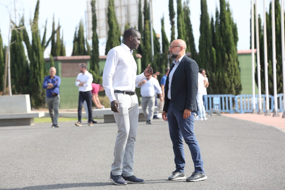 consejero de Deportes del Cabildo de Gran Canaria","Dos hombres conversan en el exterior del Club Baloncesto Gran Canaria, rodeados de árboles.