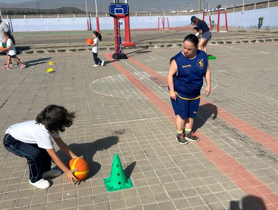 Niños jugando al baloncesto en una cancha, con porterías y conos de entrenamiento.