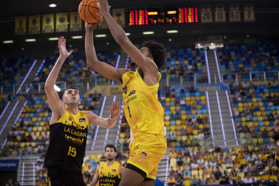 Jugador del Dreamland Gran Canaria lanza a canasta mientras es defendido por un oponente.