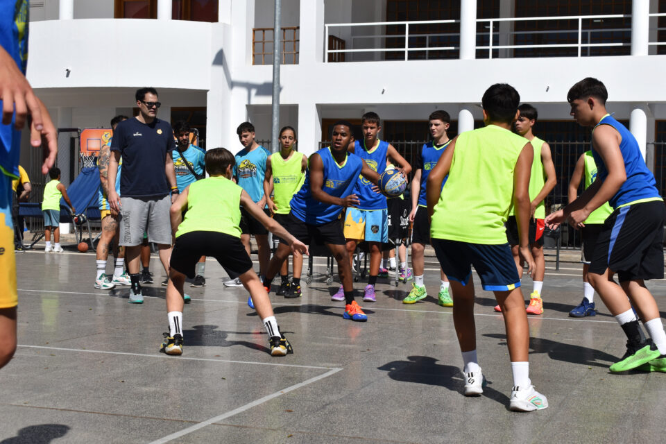 Chicos entrenando baloncesto al aire libre con monitores en la Plaza de Las Ramblas.