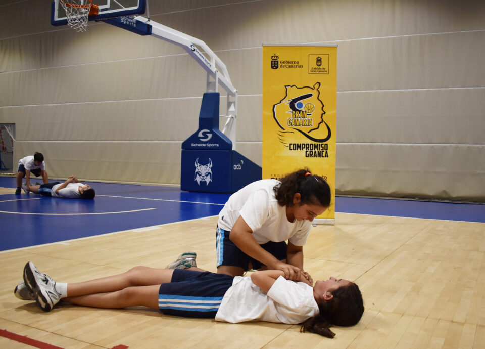 Niña recibiendo primeros auxilios en una cancha de baloncesto durante un evento.