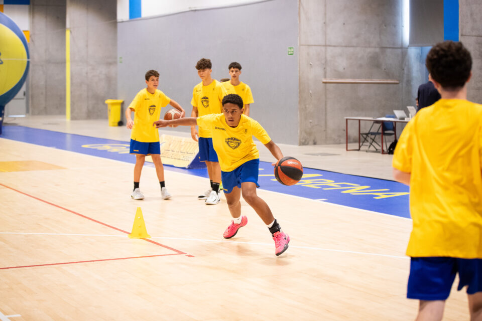 Jugadores entrenando en la II CBGC Summer Academy, practicando con balones en la cancha.