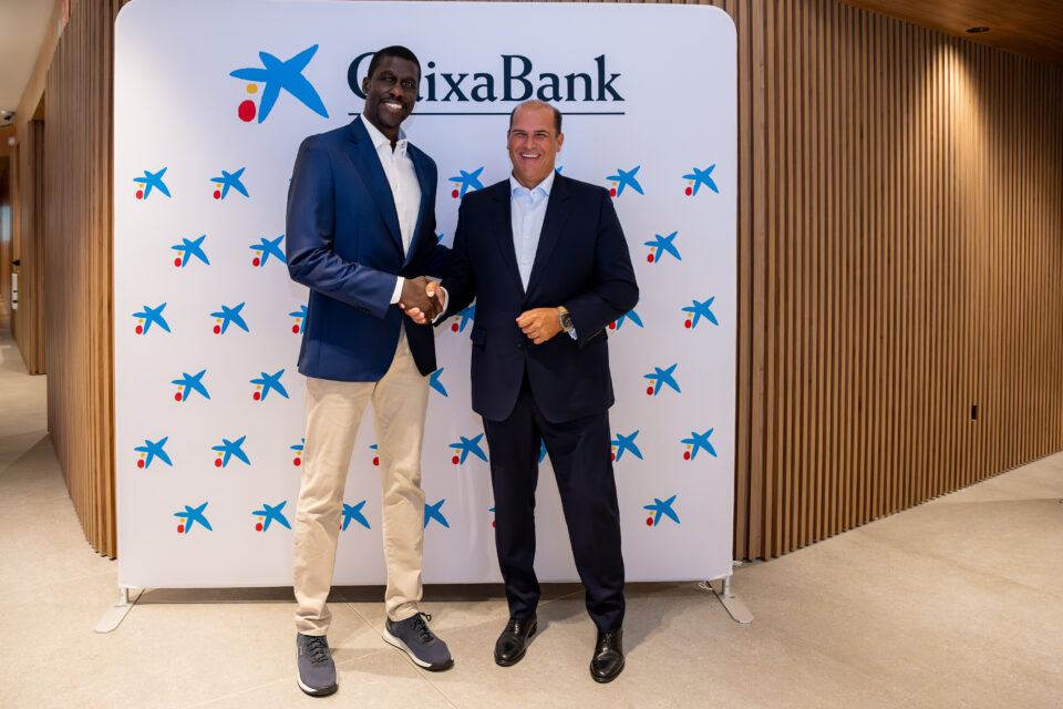 Dos hombres se estrechan la mano frente a un fondo de marca de CaixaBank.