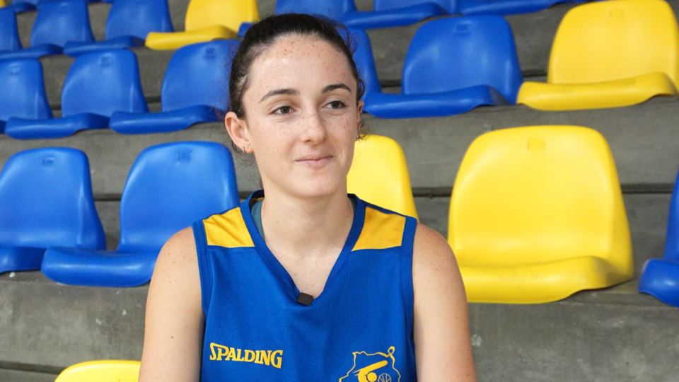 Jugadora del Gran Canaria ULPGC sentada frente a gradas azul y amarilla.