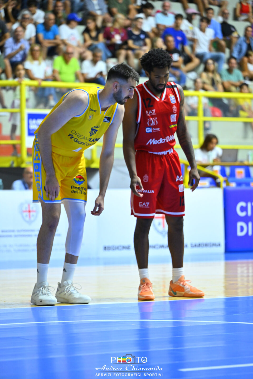 Dos jugadores de baloncesto en el campo, uno con camiseta amarilla y el otro en rojo.