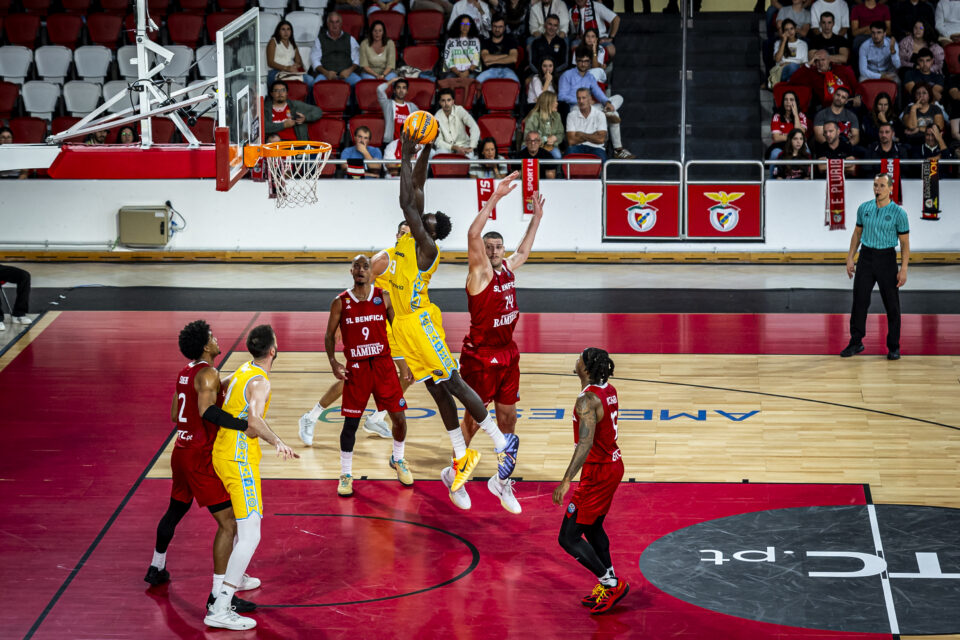 Jugador del Gran Canaria lanza a canasta mientras es defendido por oponentes.